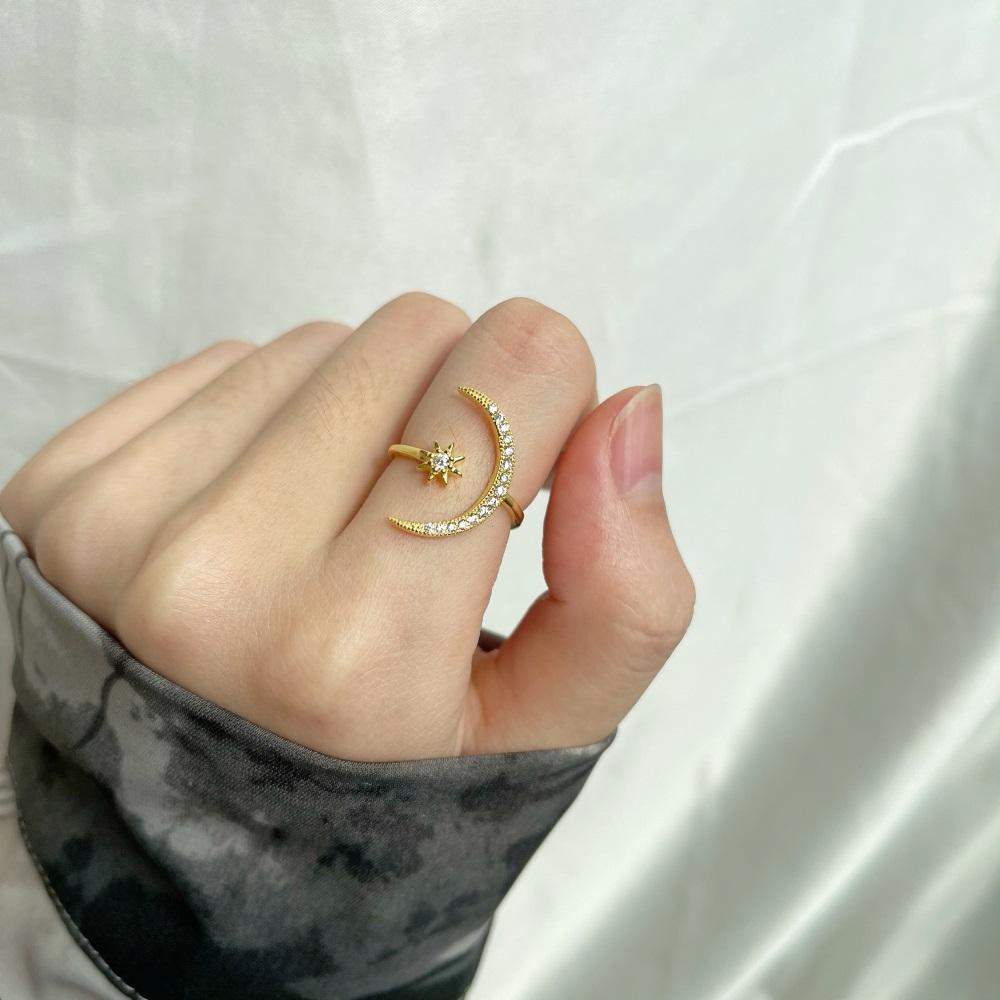 A gold-colored sterling silver ring featuring a crescent moon and a star design with sparkling stones set in the moon and star shapes.