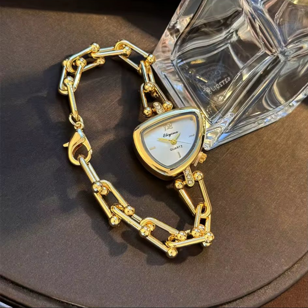 Gold chain-link watch with a oval-shaped face on a dark background