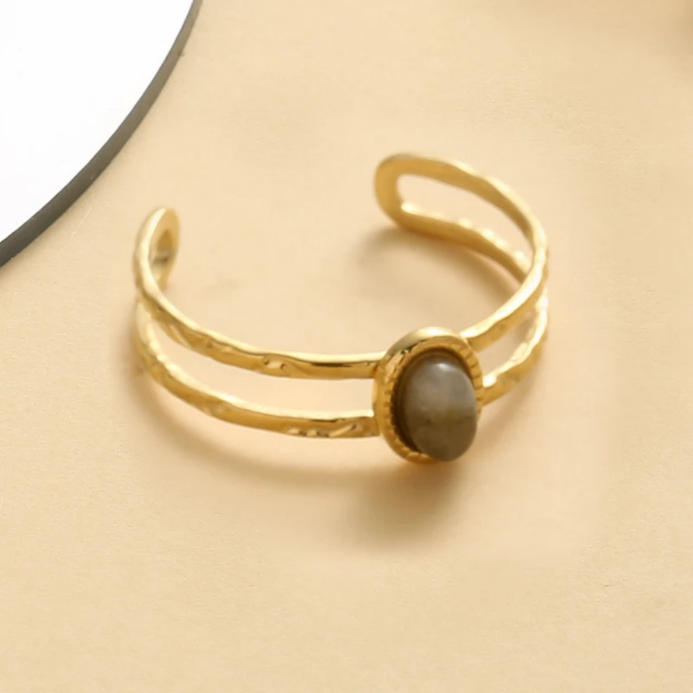 Gold ring with a central stone on a beige background