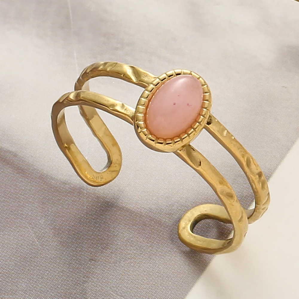 Gold ring with a pink stone on a light fabric background