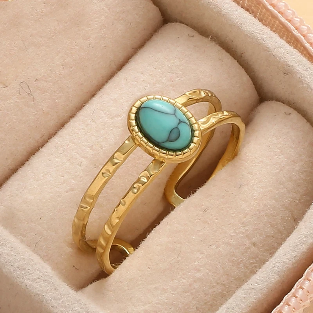 Gold ring with a turquoise stone on a beige jewelry display