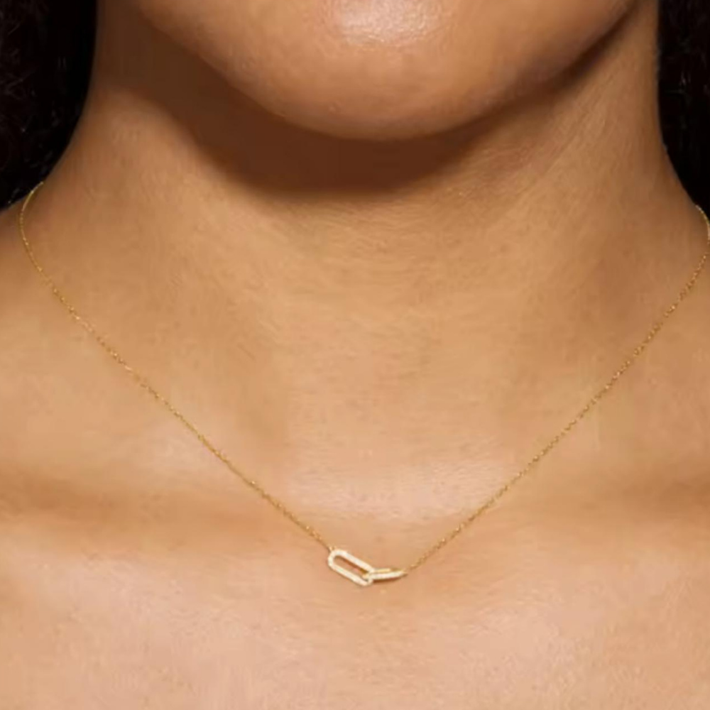 Gold necklace on a person's neck with a dark background