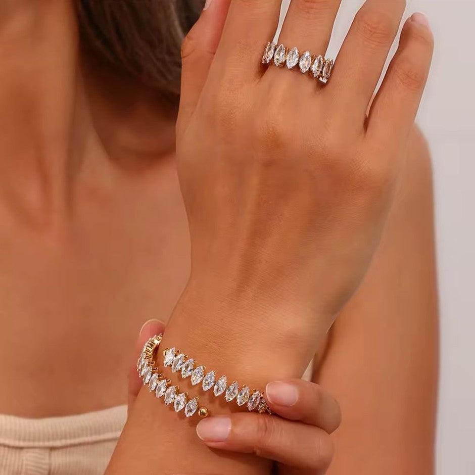 Gold ring and bracelet with clear stones on a female's hand with blurred background.