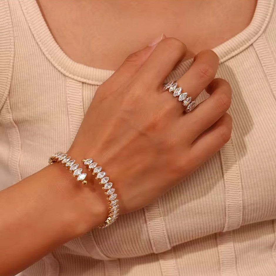 Gold bracelet and ring with clear stones placed on a women.