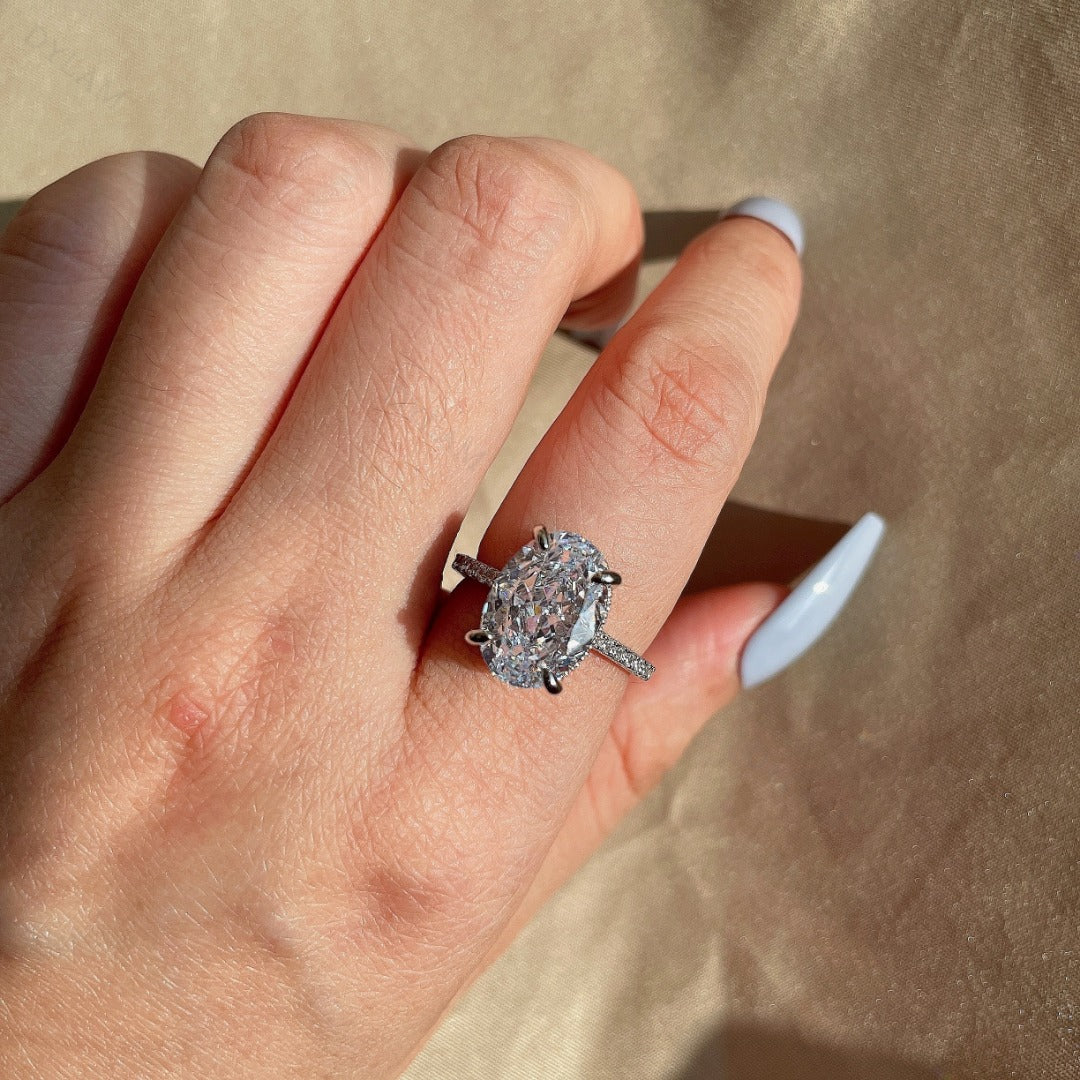An oval-shaped diamond simulant CZ stone ring with a pave band, predominantly silver in color.