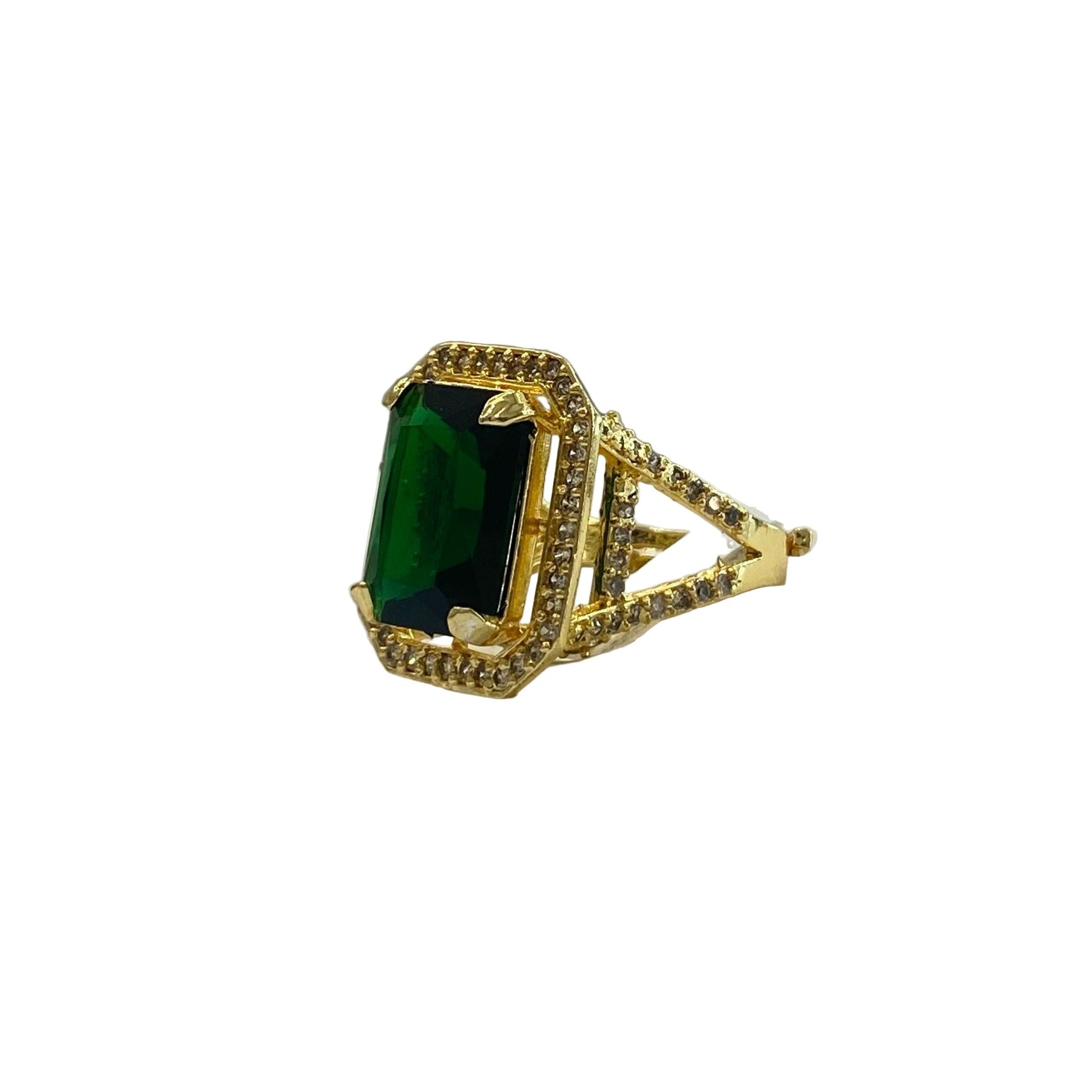 An elegant emerald green gemstone ring with a gold-colored band, featuring intricate detailing, displayed on a white square pedestal.