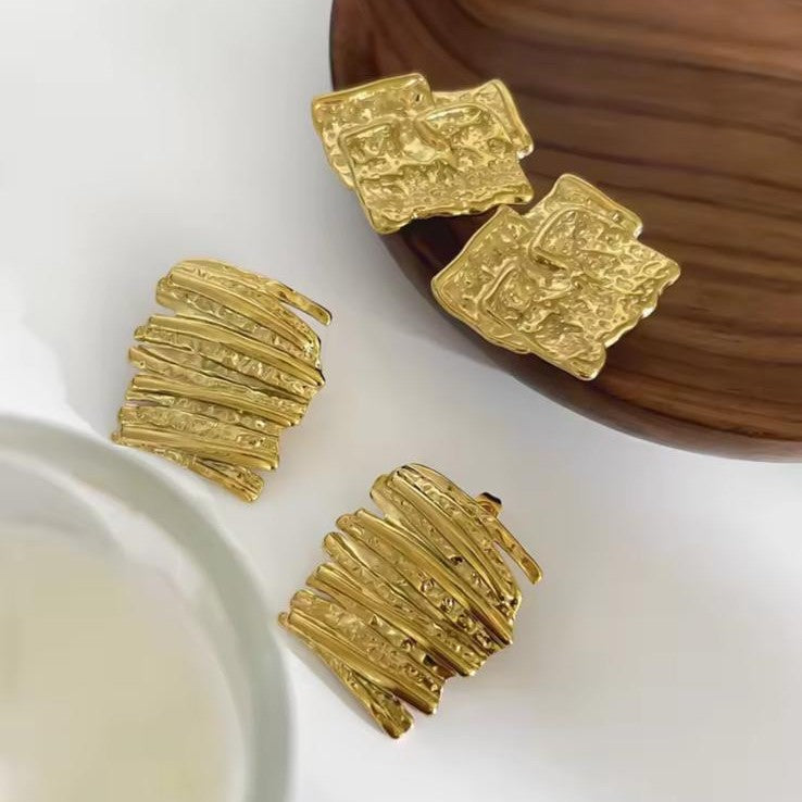 Gold earrings with textured design on a white surface