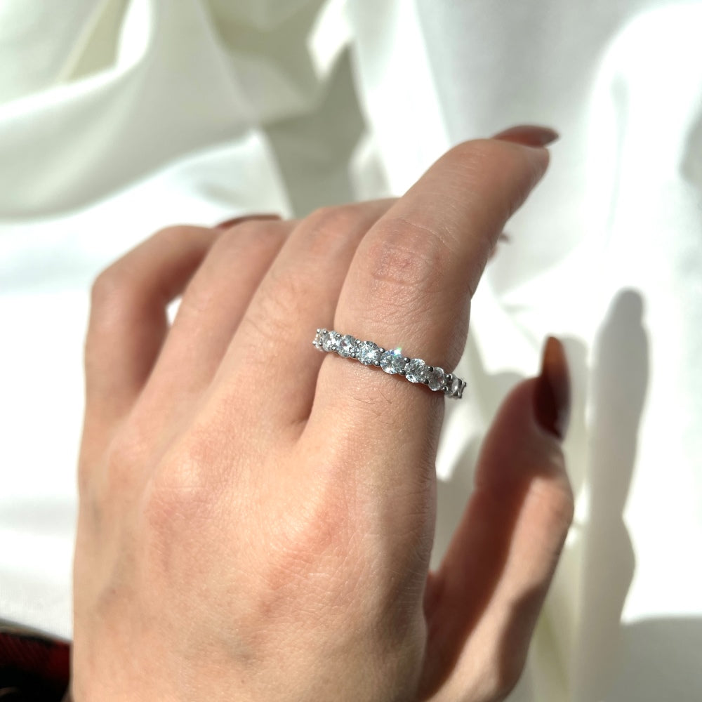 A silver band eternity ring with round-cut cubic zirconia stones set around its entire circumference.