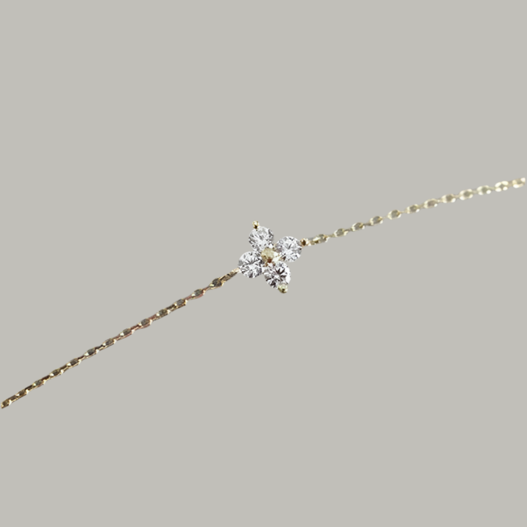 Gold bracelet with a diamond flower clasp on a gray background