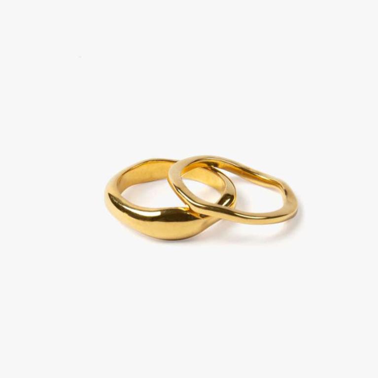A gold-colored band ring with a wavy design, made from stainless steel, displayed on a plain background.