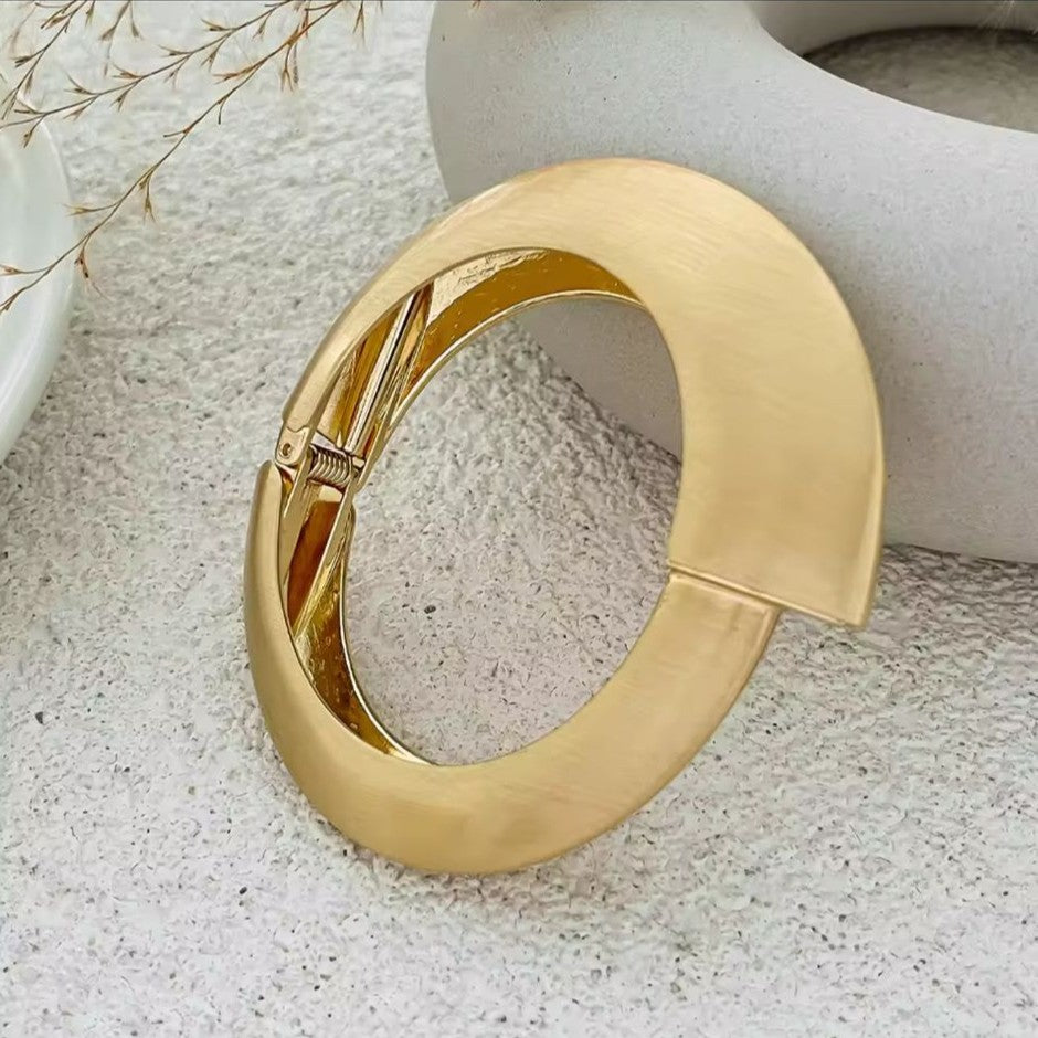 Gold bangle on a textured surface with a neutral background
