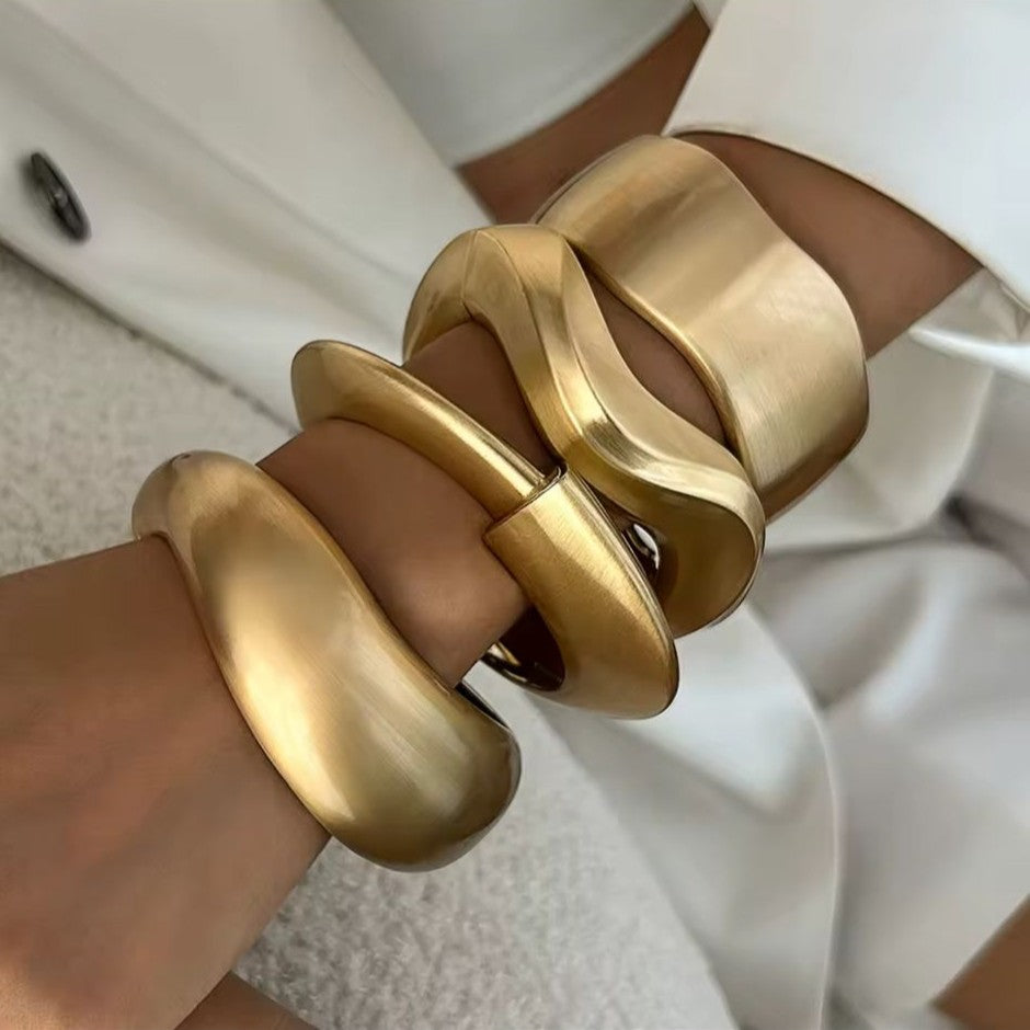 Gold bangles on a person's wrist with a blurred background