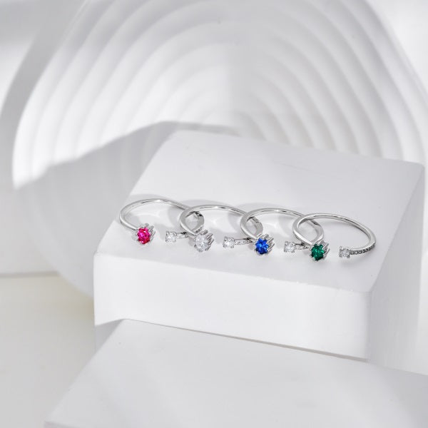 A collection of adjustable silver rings with a multicolor, ornate designs around the central stone placed on a white background.