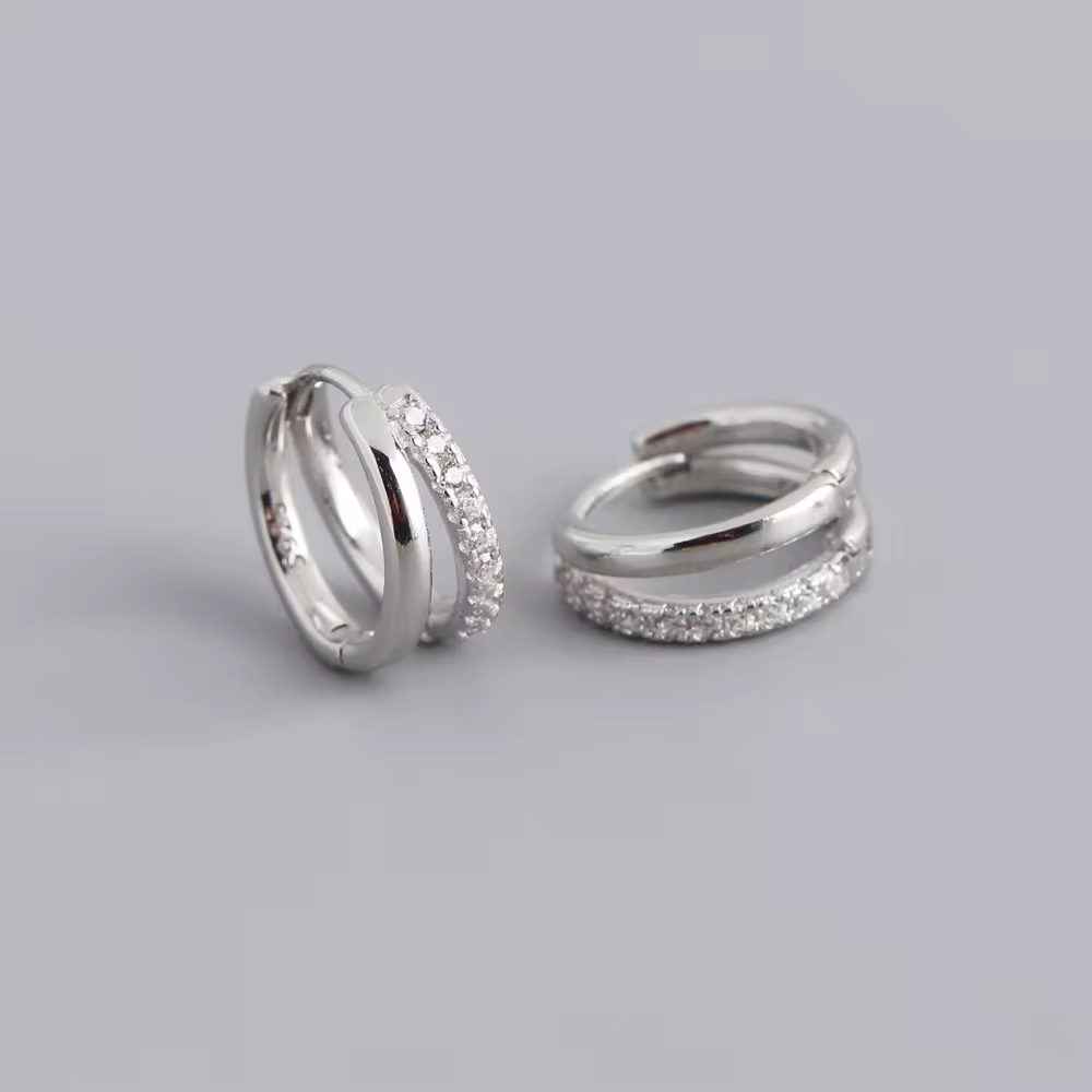 Pair of silver hoop earrings with embedded stones on a light gray background