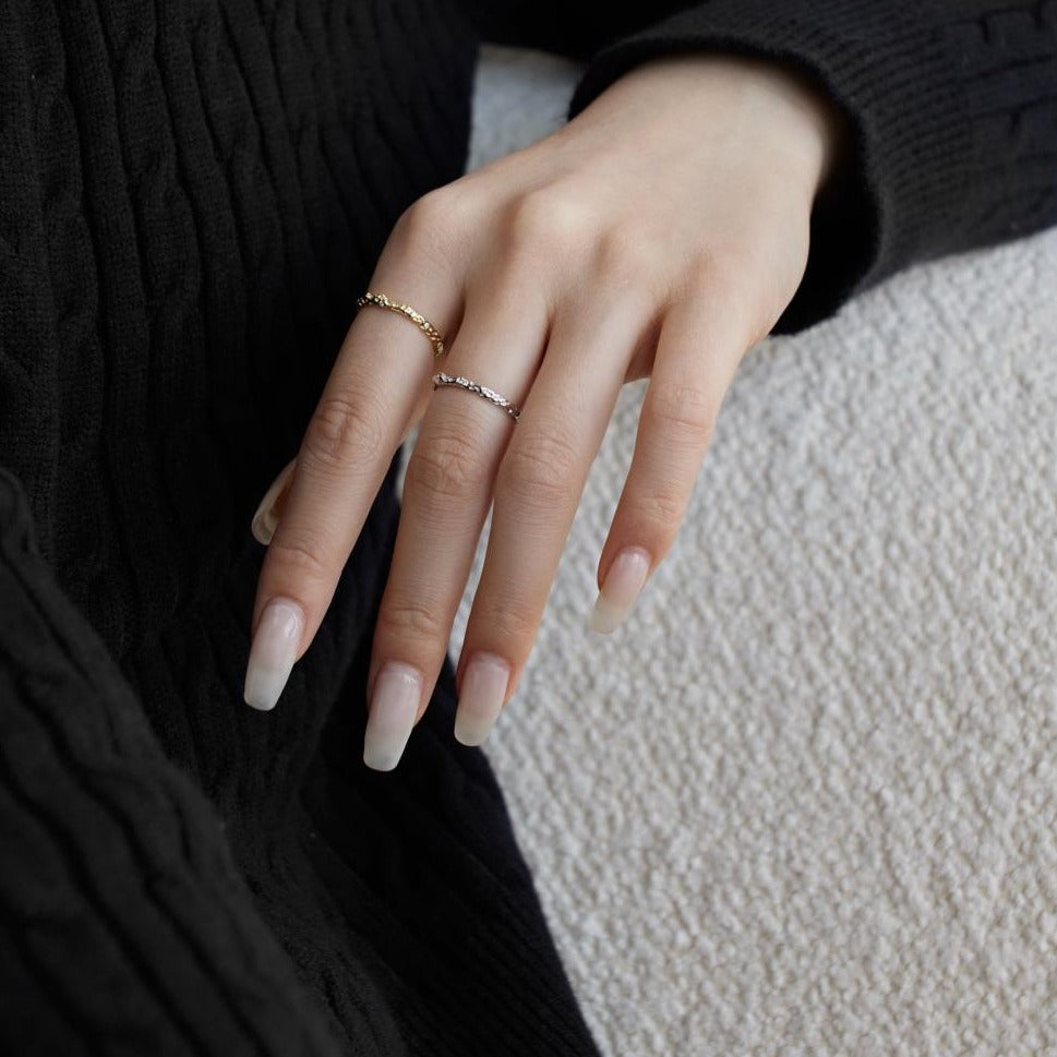 A pair of silver and gold-colored adjustable ring with a textured surface and embedded transparent stones.