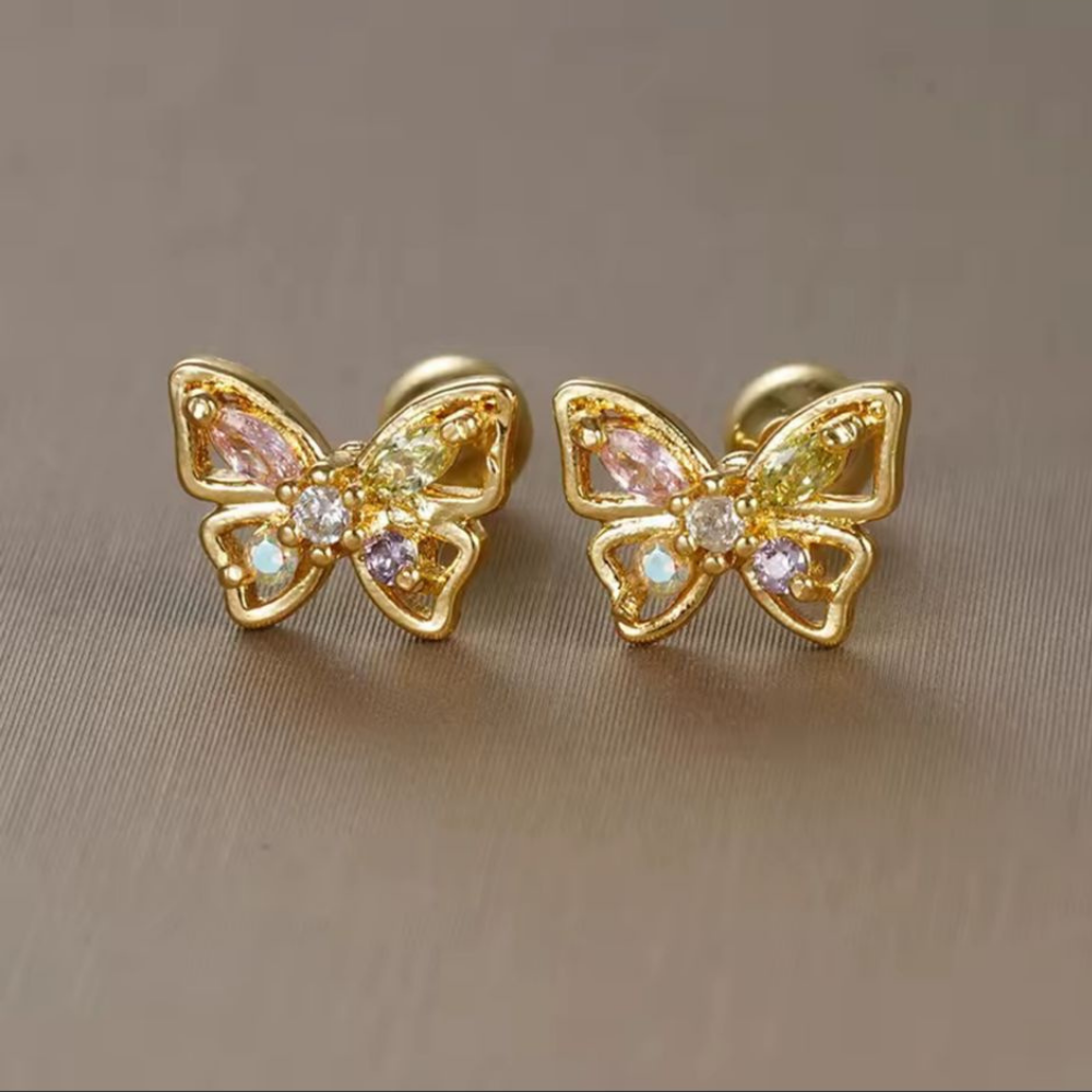 Gold butterfly earrings with gemstones on a beige background