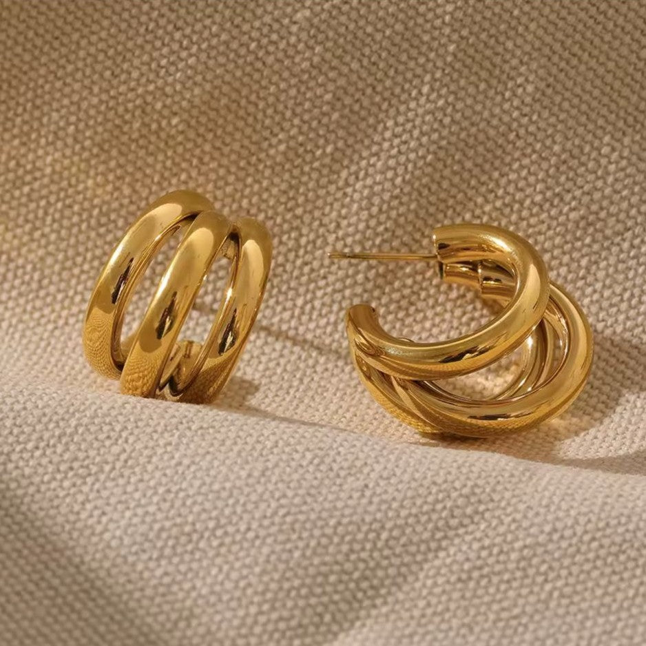 Pair of gold hoop earrings on a beige fabric background