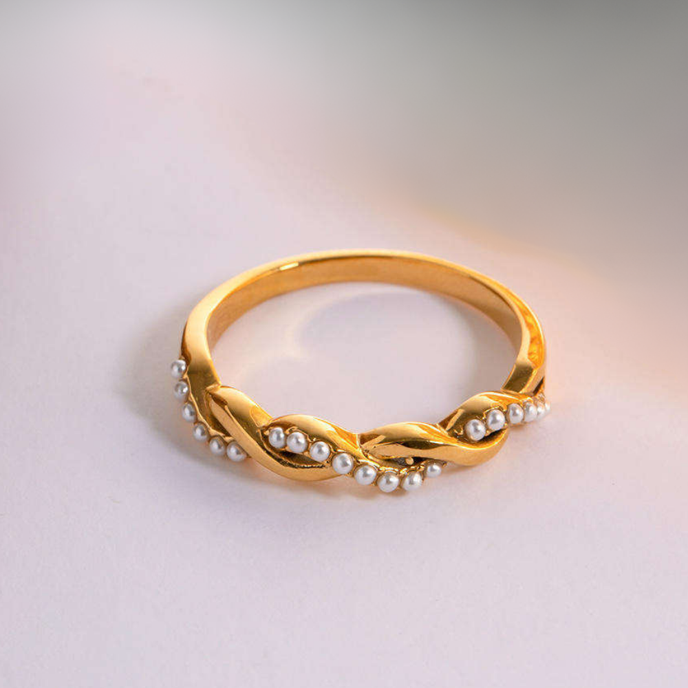 Twisted Gold ring with pearl accents on a light background