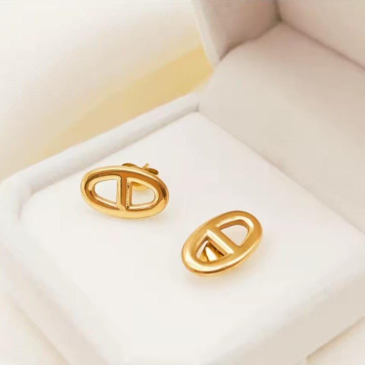 Gold earrings on a light beige background