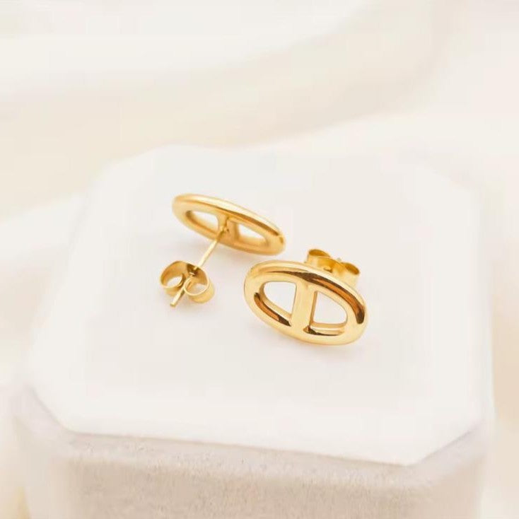 Gold earrings on a white cushion