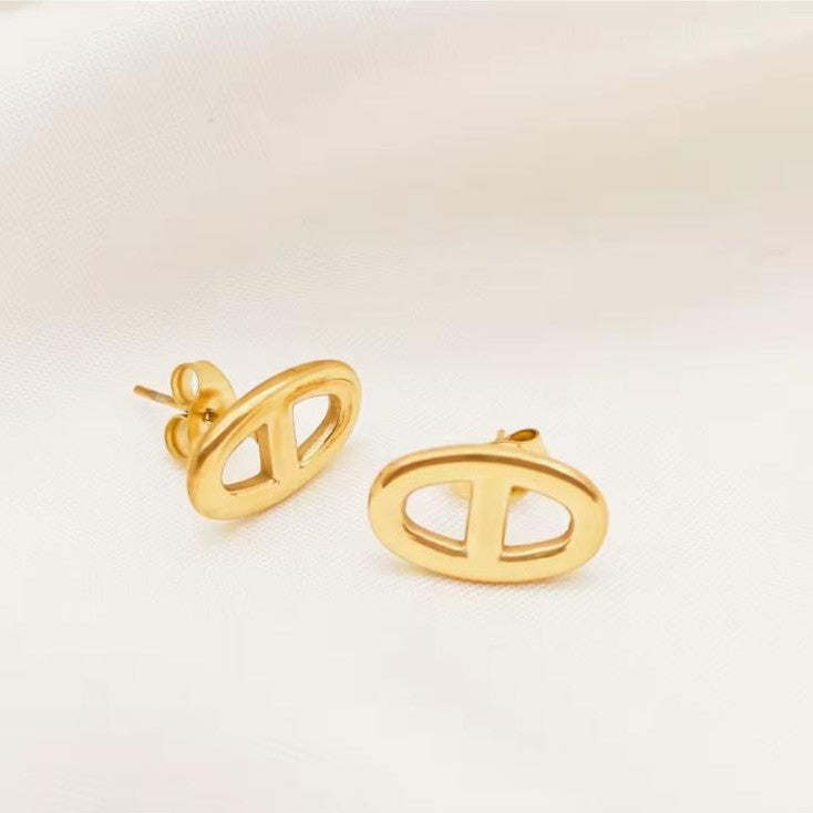 Gold earrings on a light beige background