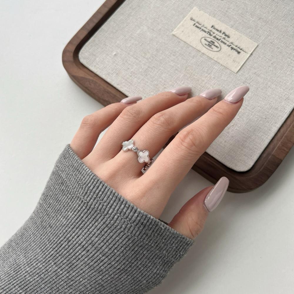 A white shell clover ring with gold/silver plating on sterling silver, with small clear stones accents.