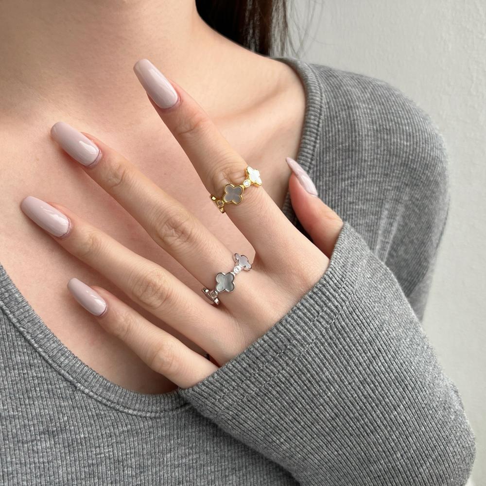 A pair of white shell clover rings with silver and gold plating on sterling silver, with small clear stones accents.