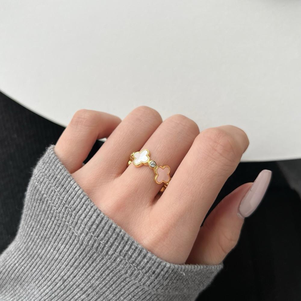 A white shell clover ring with gold plating on sterling silver, with small clear stones accents.