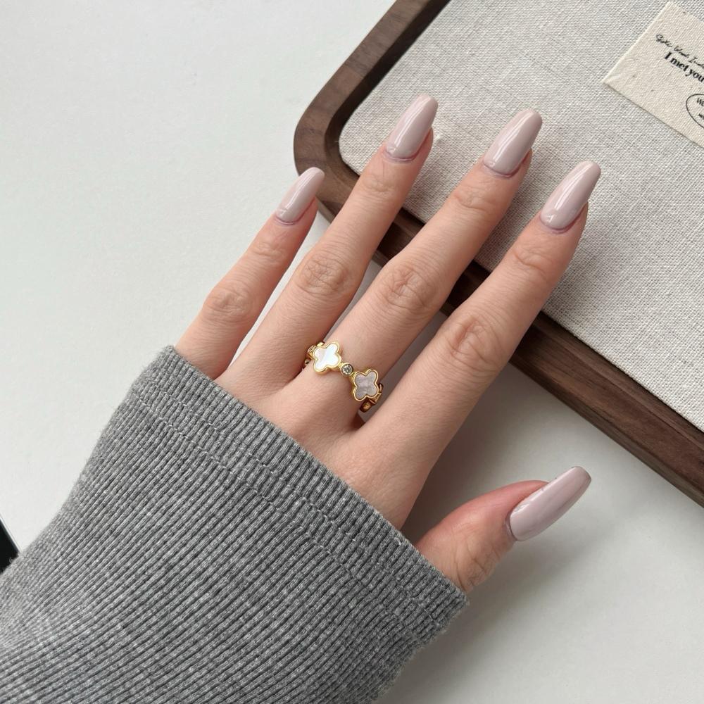 A white shell clover ring with gold plating on sterling silver, with small clear stones accents.