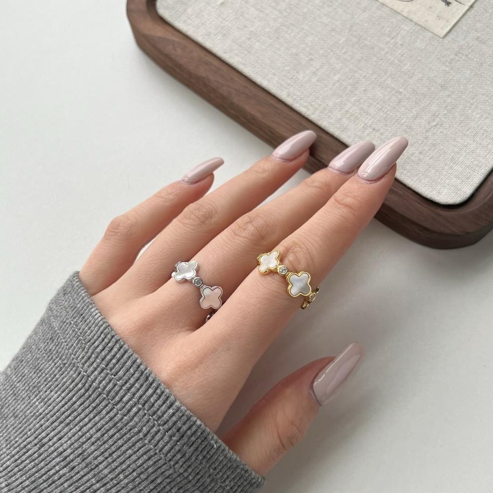 A pair of white shell clover rings with silver and gold plating on sterling silver, with small clear stones accents.