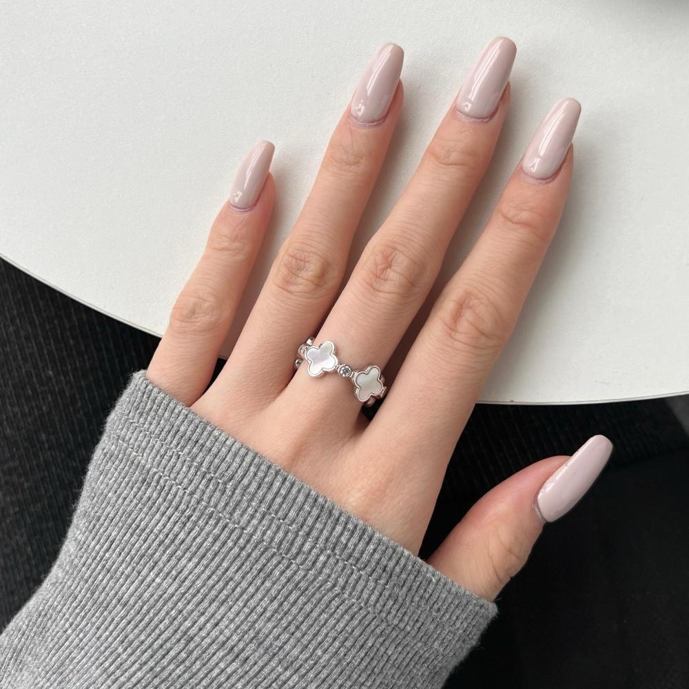 A white shell clover ring with silver plating on sterling silver, with small clear stones accents.