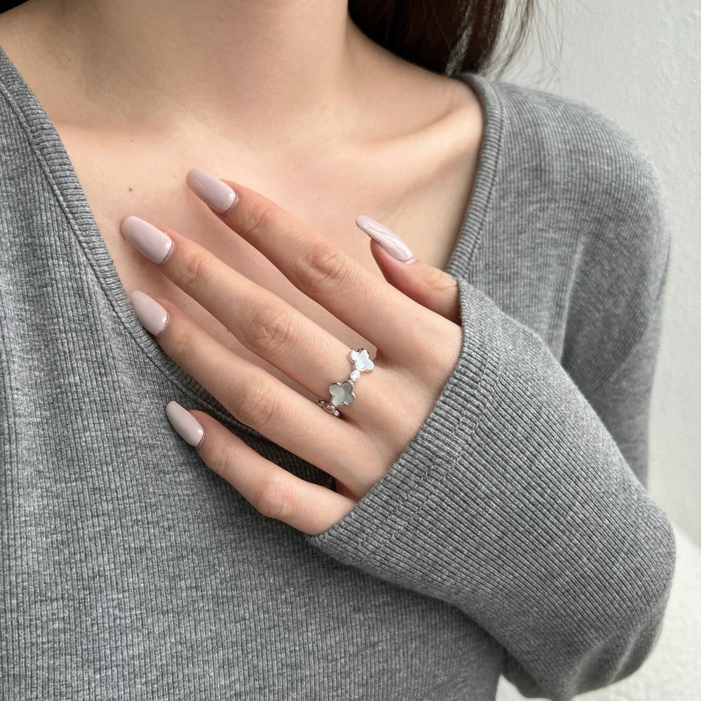 A white shell clover ring with silver plating on sterling silver, with small clear stones accents.