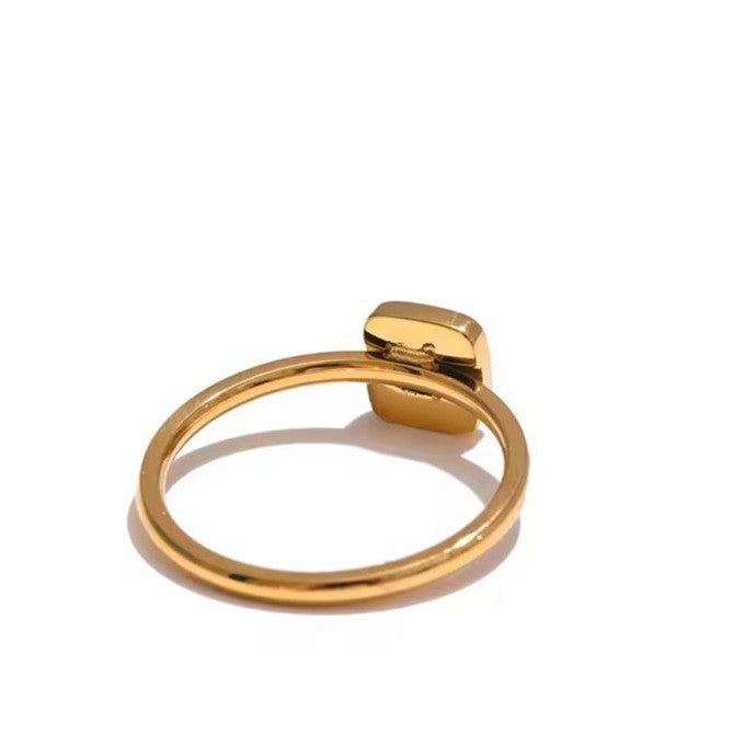 Gold ring with a central gemstone on a white background