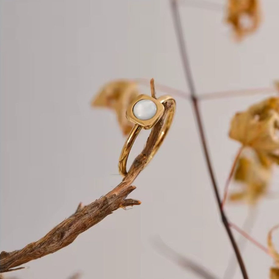 Gold ring with a stone on a branch against a blurred natural background