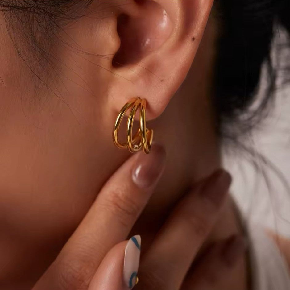 A bold hoop earring in gold-plated modern style on a women's ear.