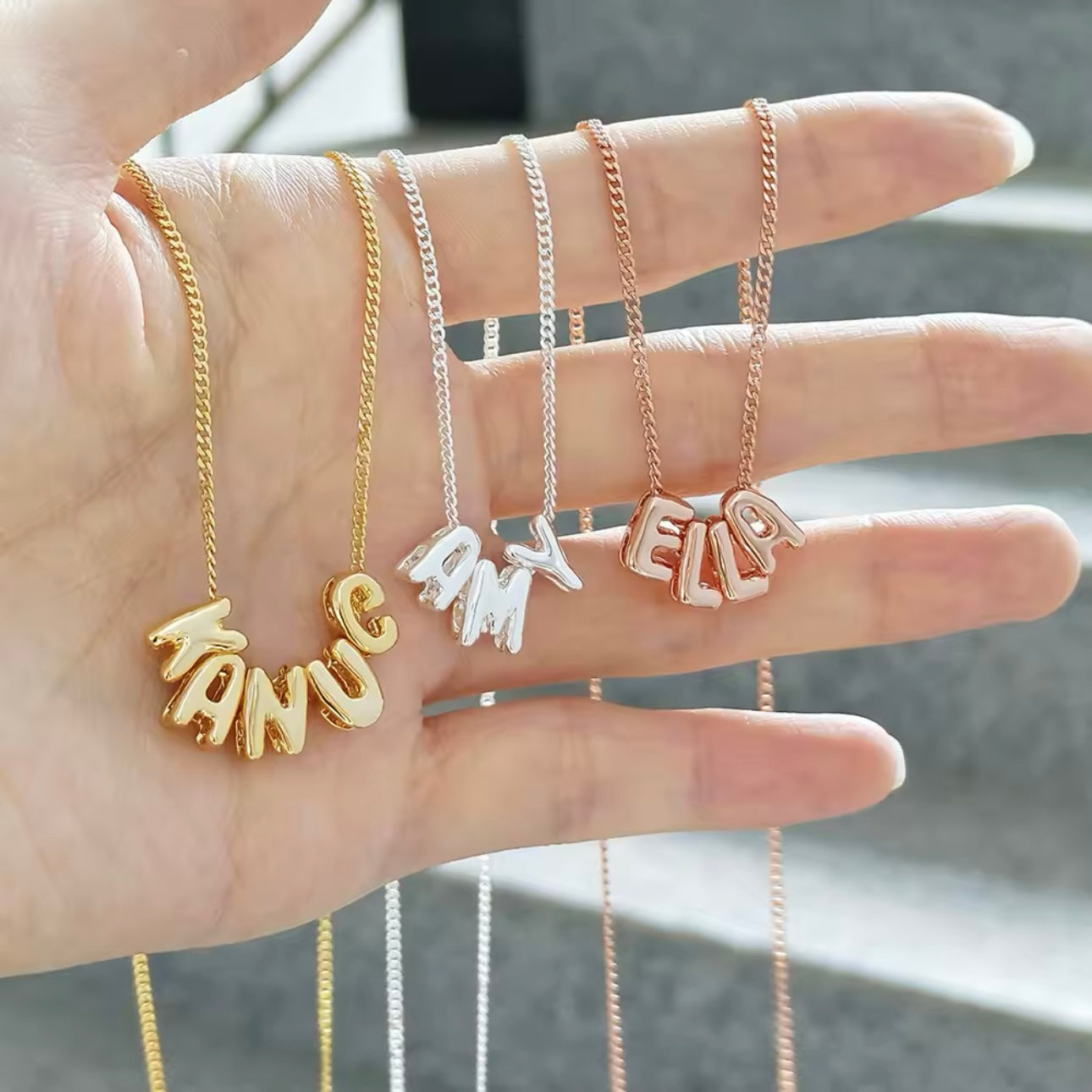A gold, bronze and silver bubble charm necklaces spelling personalized names.