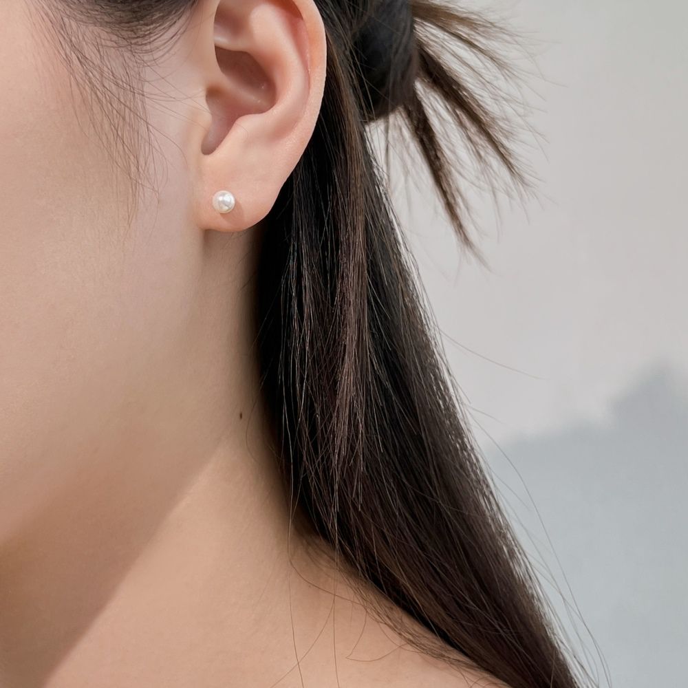 A classic pearl stud earring with lustrous pearls set presented on a women's ear.