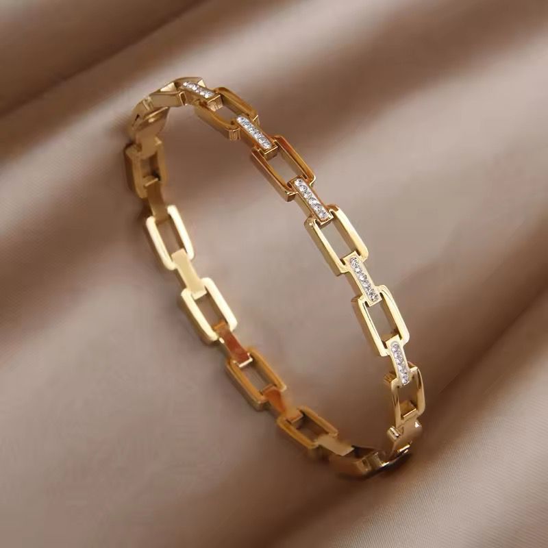 A gold-colored stainless steel bracelet with a hollow geometric pattern.