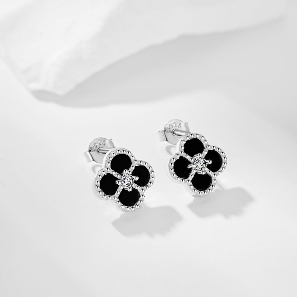 A pair of clover-shaped stud earrings with black and white stones set in a rhodium-plated 925 sterling silver band.