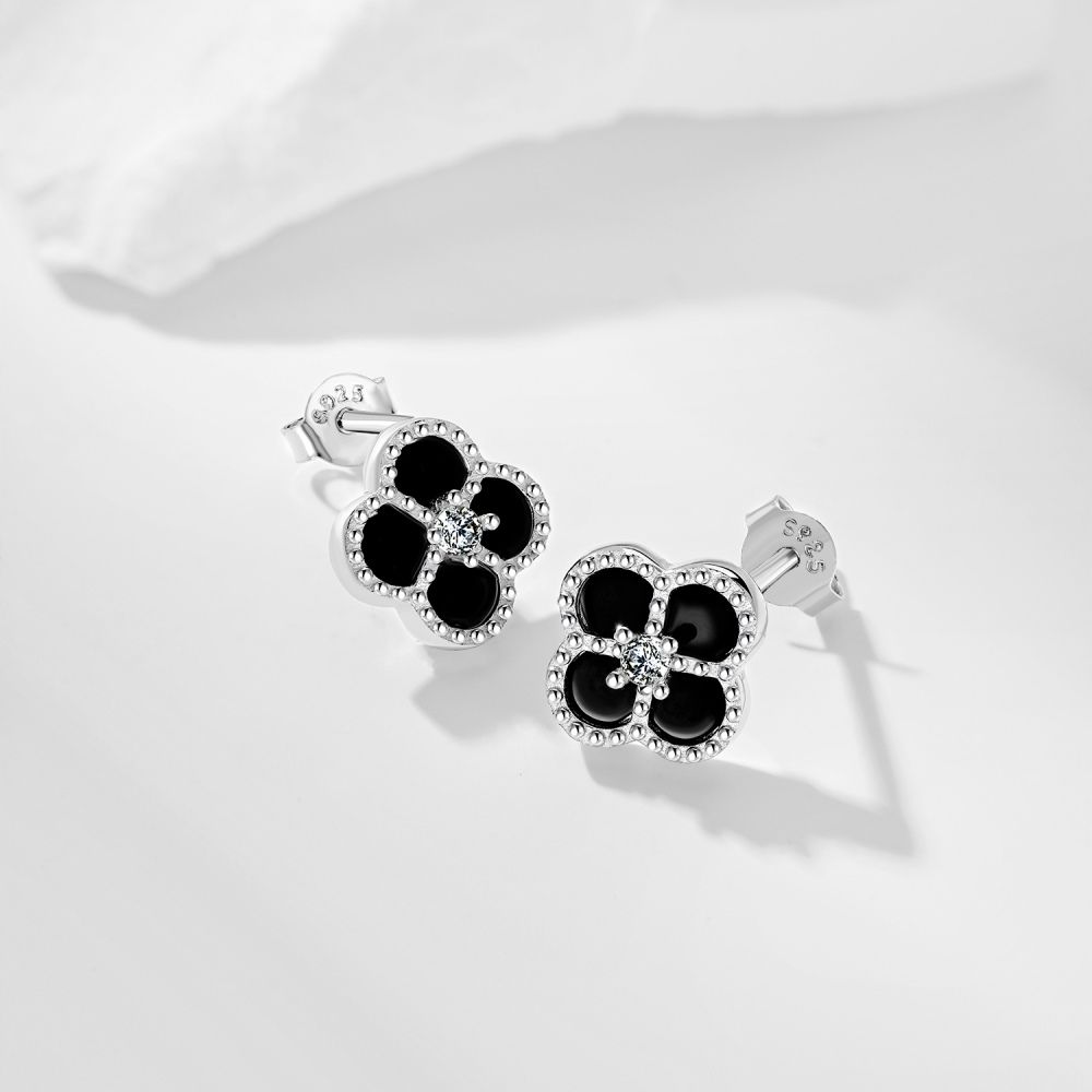 A pair of clover-shaped stud earrings with black and white stones set in a rhodium-plated 925 sterling silver band.