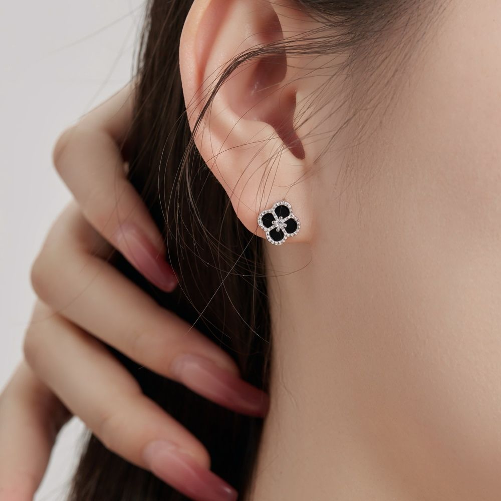 A clover-shaped stud earring with black and white stones in a rhodium-plated 925 sterling silver band.