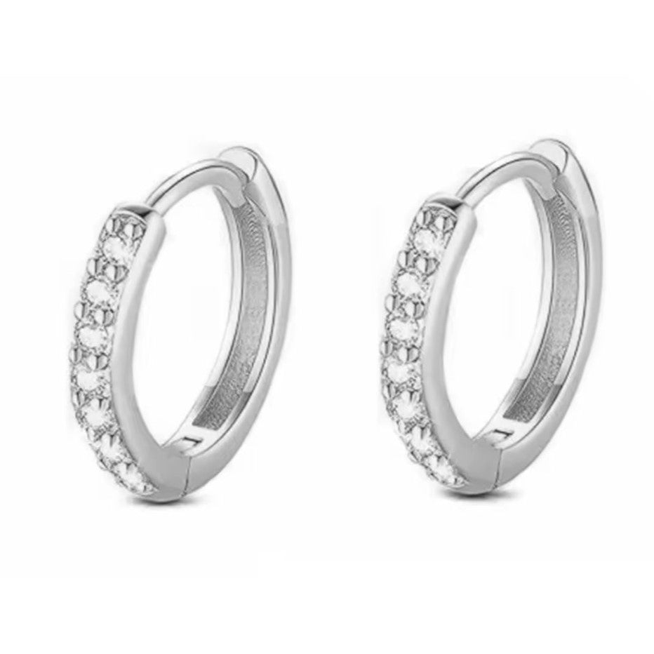 A pair of stainless steel huggie hoop earrings with crystals adorning the band.