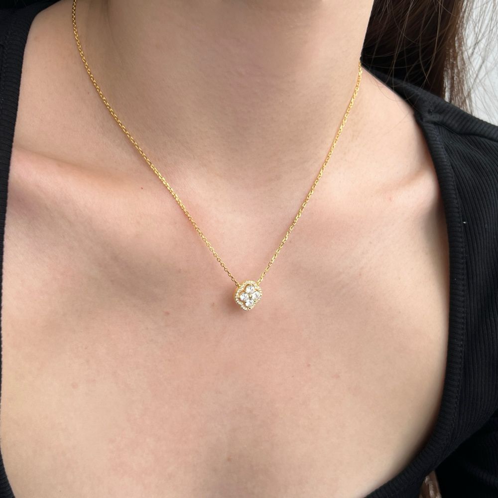 A gold-plated clover necklace with 5A-grade zircon stones on a gold chain presented on a women's neck.