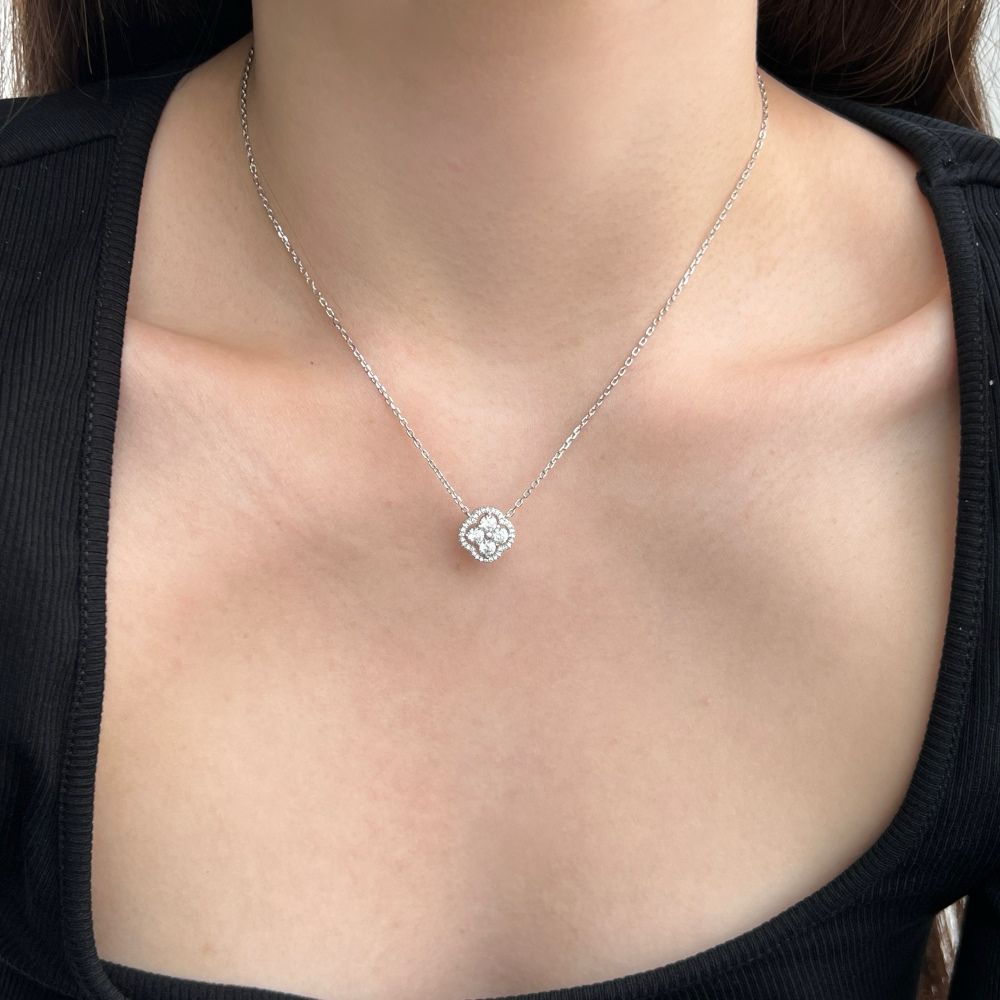 A gold-plated clover necklace with 5A-grade zircon stones on a silver chain presented on a women's neck.