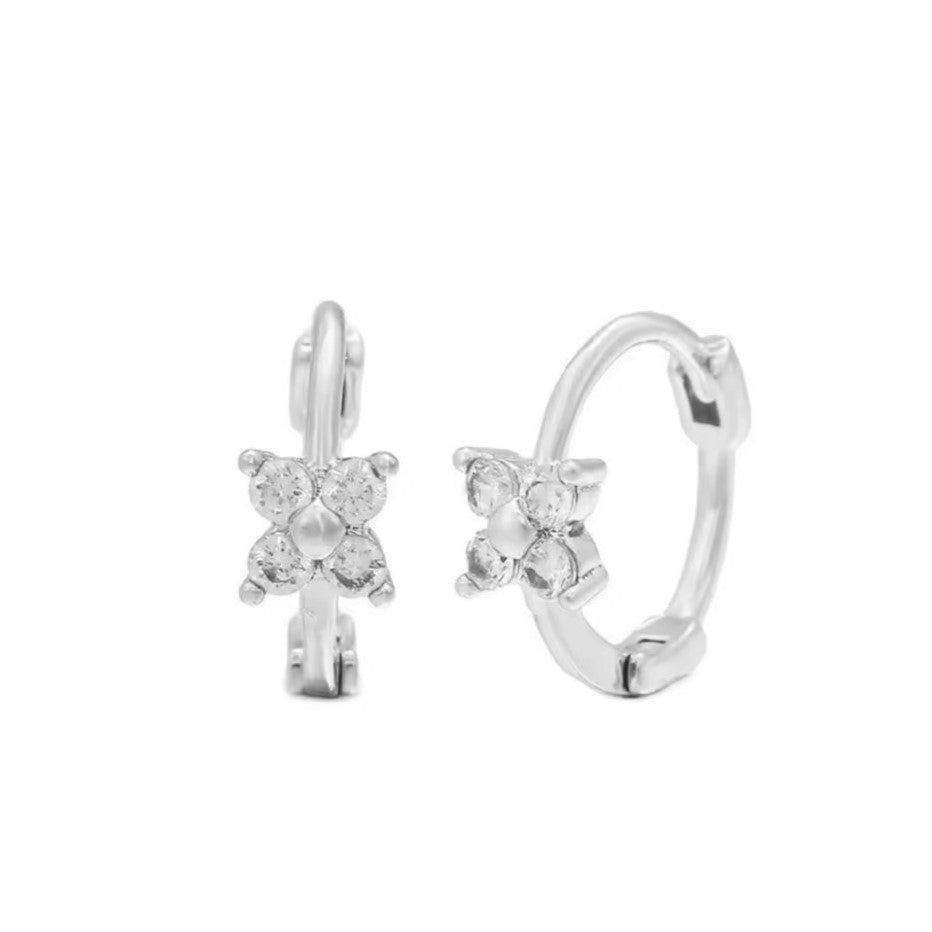 A pair of silver-colored huggie hoop earrings with a daisy design, crafted from stainless steel.
