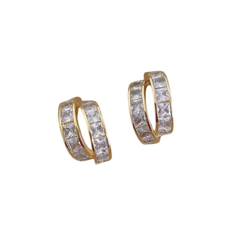 A pair of gold-tone huggie hoop earrings with a double row of square-cut crystals, displayed on a white.