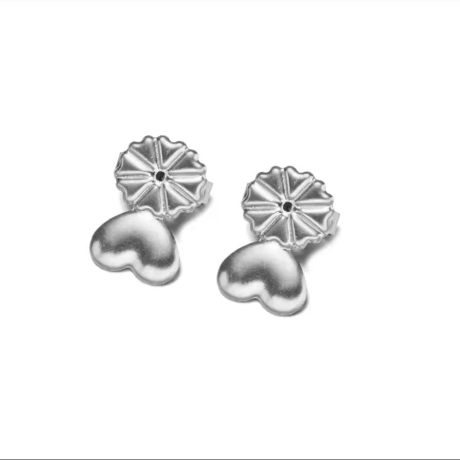 A pair of silver-colored earring lifters with a heart-shaped design, intended for use with post earrings to provide support and lift.
