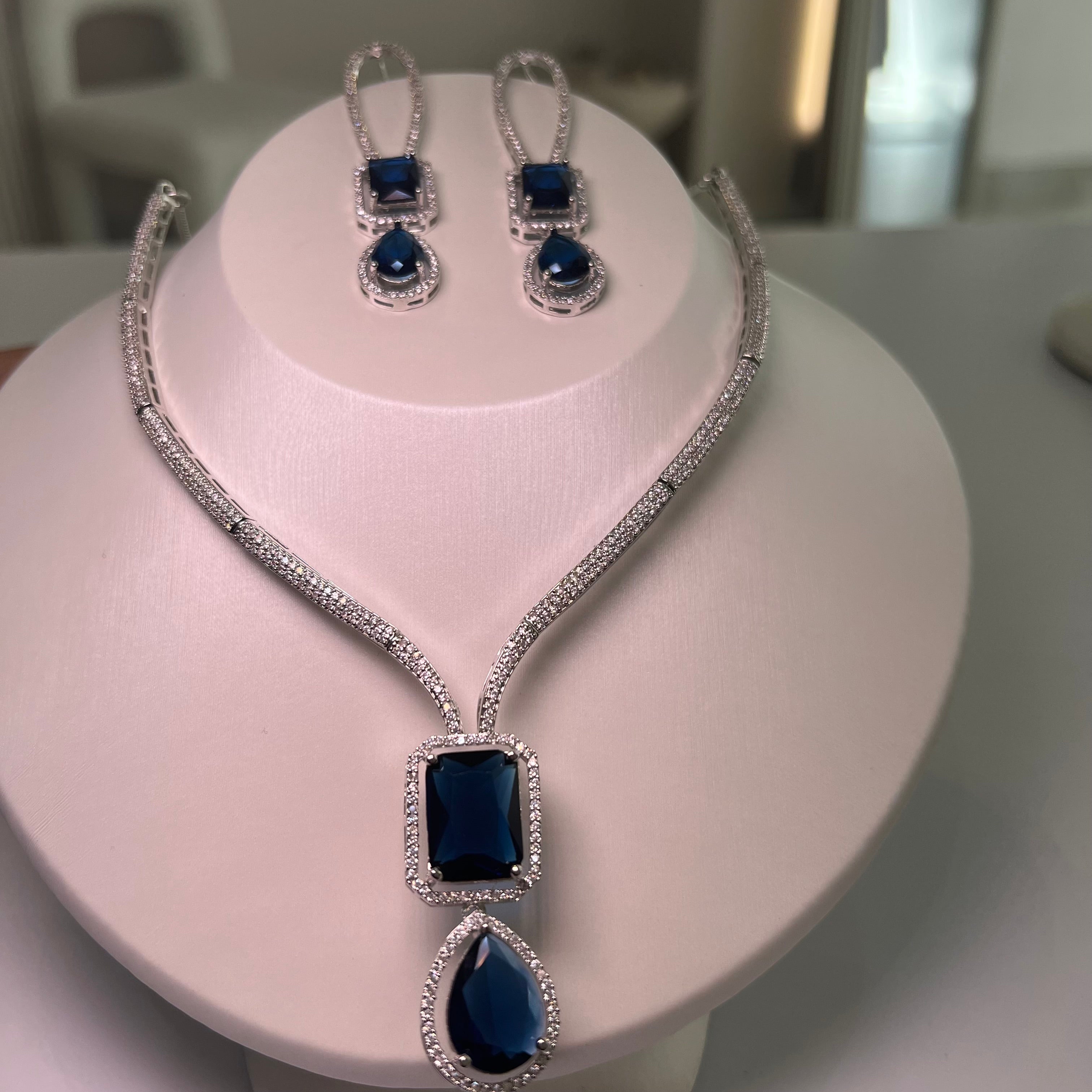 A silver-tone Empire Drape Necklace and Earrings set with blue gemstone pendants displayed on a mannequin bust