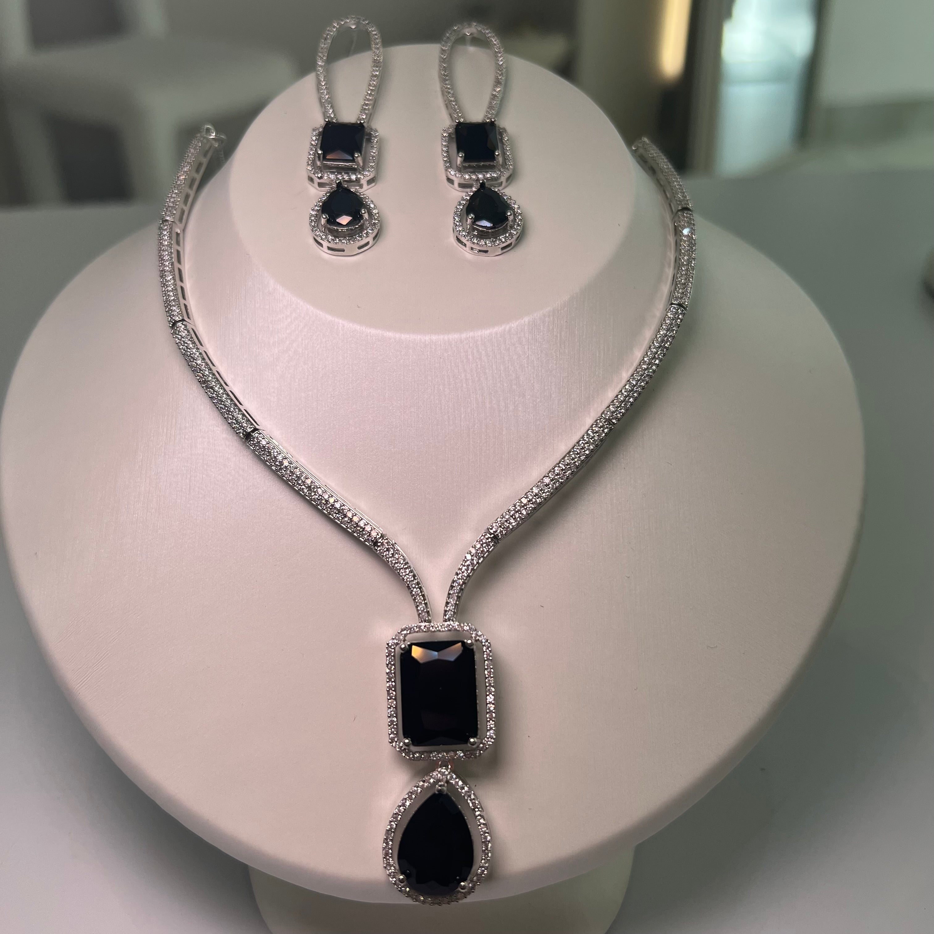 A silver-tone Empire Drape Necklace and Earrings set with black gemstone pendants displayed on a mannequin bust