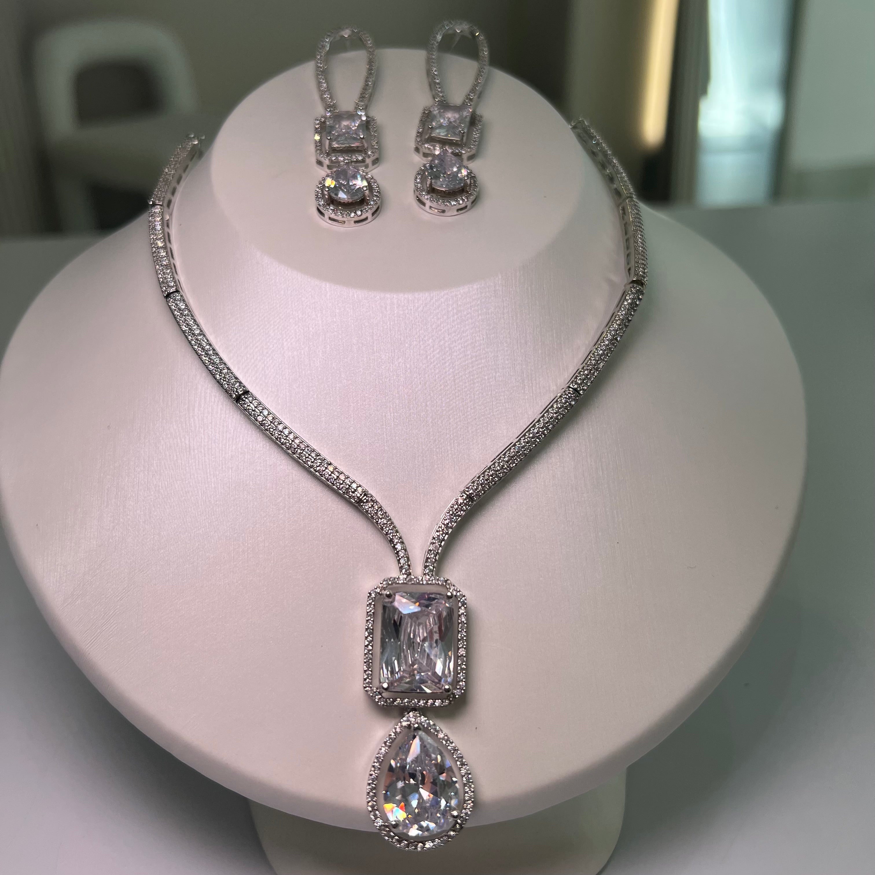 A silver-tone Empire Drape Necklace and Earrings set with clear gemstone pendants displayed on a mannequin bust